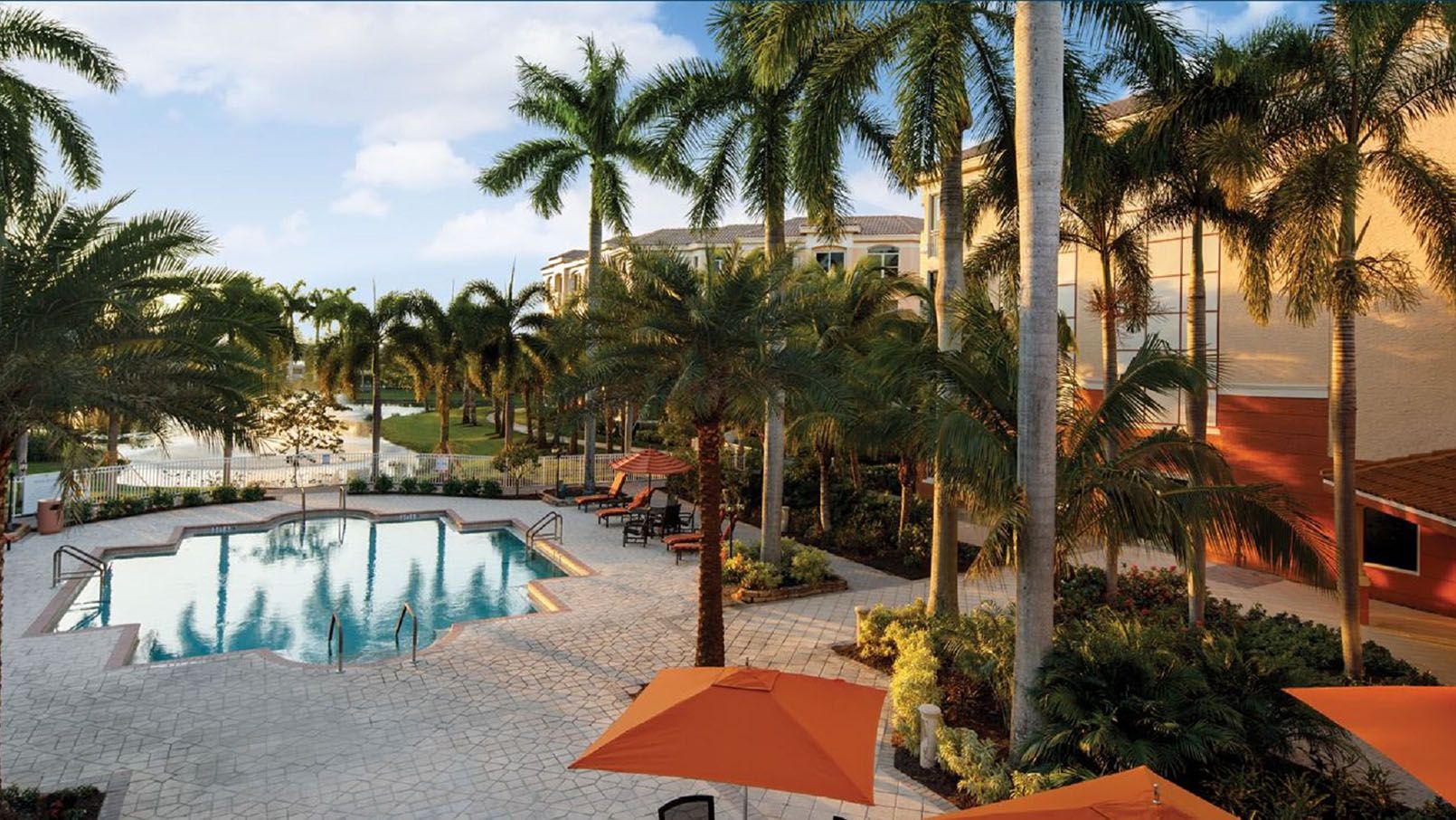 Luxurious swimming pool surrounded by palm trees at the premier Devonshire at PGA National in Palm Beach Gardens, Florida.