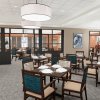 Bright private dining space with neatly set tables, large windows, and residents seated for a quiet meal.