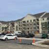Wide view of finished apartment complex with parked vehicles, construction equipment, and workers on site
